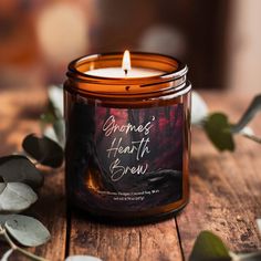 a candle that is on top of a wooden table next to some plants and leaves