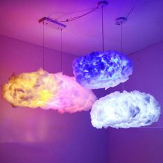 three different colored lights hanging from the ceiling in a room with white walls and purple lighting