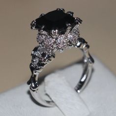 a black diamond ring sitting on top of a white napkin