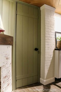 a white brick wall and green door in a room with wood ceiling tiles on the floor