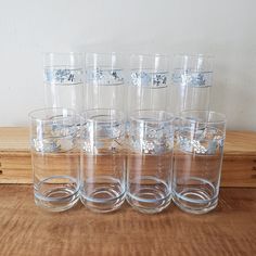 six clear glasses sitting on top of a wooden table