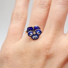 Darling 14k yellow gold and cobalt blue enamel pansy that has been converted into a ring from an antique stick pin. Enamel is in excellent condition. Pansy houses a small 3mm diamond in the center. Ring size 4.5. Sizing available Layaway available Blue Hallmarked Enamel Ring, Blue 14k Gold Enamel Ring For Formal Events, Blue 14k Gold Enamel Ring For Formal Occasions, Formal Blue Enamel Ring In 14k Gold, Yellow Gold Enamel Flower Jewelry, Fine Jewelry Enamel Ring Hallmarked, Blue Enamel Ring In 14k Gold, Round Shape, Blue Enamel Ring In 14k Gold, Anniversary Yellow Gold Enamel Ring In Sterling Silver