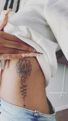 a woman's stomach with a lotus tattoo on her belly and the bottom part of her lower back