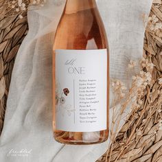 a bottle of wine sitting on top of a table next to some dried grass and flowers