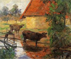 two cows are standing by a fence in front of a house and trees, near a body of water