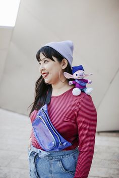 a woman with a stuffed animal on her back and a blue bag around her neck