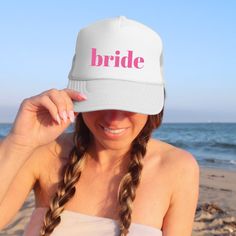 a woman wearing a white hat with the word bride on it and pink letters in front of her face