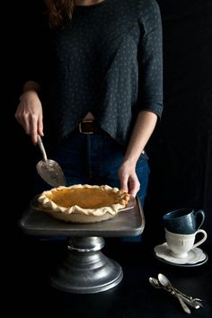 a woman cutting into a pie on top of a metal pan