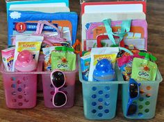 three plastic baskets filled with baby items on top of a wooden table next to each other