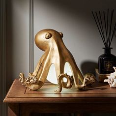 a gold sculpture sitting on top of a wooden table next to a bottle and vase