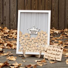 a photo frame with wooden circles on it next to some cards and leaves in front of a wood fence