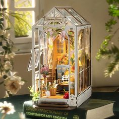 a miniature house sitting on top of a green table next to a potted plant