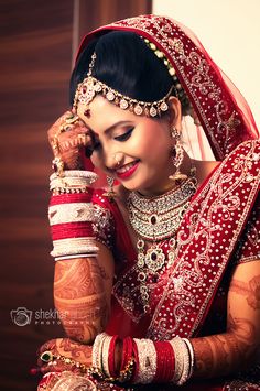 a woman in a red and gold bridal outfit holding her hands to her face