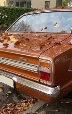 an old car is parked on the side of the road with leaves all over it