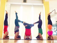 four people doing handstand on the floor with their arms in the air and one standing up