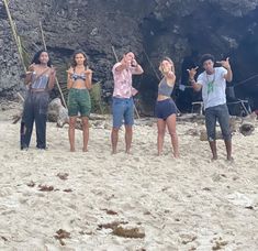 four people standing on the beach taking pictures