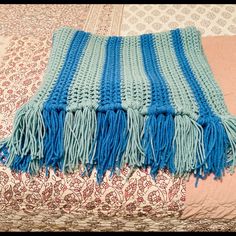 a blue and white blanket on top of a bed next to a pink comforter