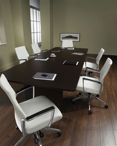 an empty conference table with white chairs around it