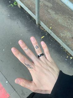 a person's hand with a ring on it and two stars tattooed on their fingers