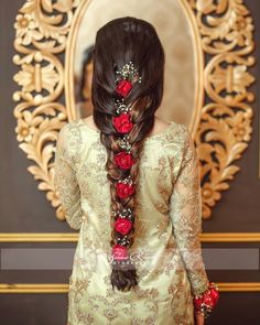 a woman with long hair and flowers in her hair, wearing an intricate braid hairstyle