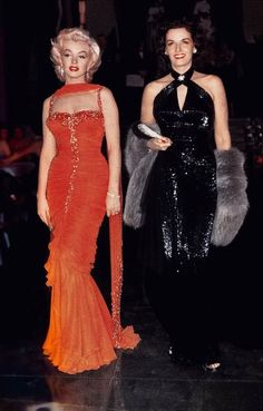 two women in evening gowns standing next to each other