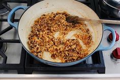 a pan filled with food sitting on top of a stove next to a wooden spoon