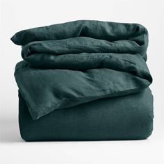 an unmade bed with dark green sheets and pillow cases on top of each other