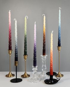 five candles are lined up in different colors and sizes, with one candle on top of the other