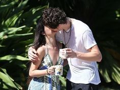 a man kissing a woman while holding a cup