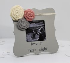 a baby photo frame with three flowers on it and the words love at first sight