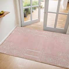 a pink area rug on the floor in front of an open door with glass doors