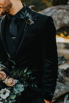 a man and woman standing next to each other in front of rocks with flowers on them