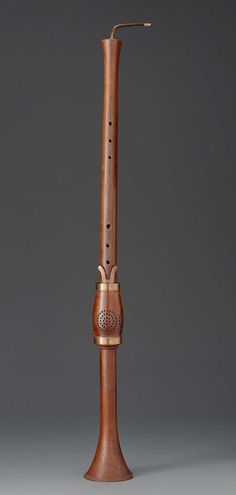 an old wooden instrument is standing upright on a gray surface, with the top part of it's mouth open