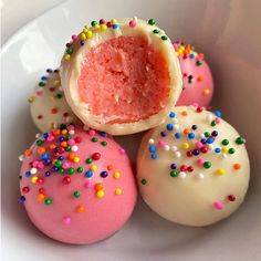 some pink and white donuts with sprinkles on them in a bowl