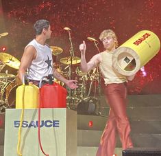 two people are performing on stage with an object in the air above their head and one person is holding a fire extinguisher