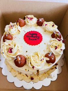 a birthday cake with white frosting and toppings in a box on a table