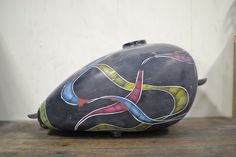 an artistically painted motorcycle helmet sitting on top of a wooden table in front of a white wall