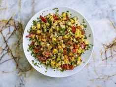 a white bowl filled with chopped vegetables on top of a marble countertop next to a knife and fork