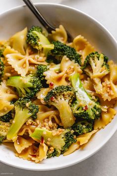 a bowl filled with pasta and broccoli on top of a white countertop