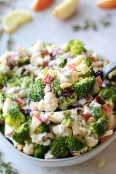 a bowl filled with broccoli salad and a spoon full of the salad is ready to be eaten