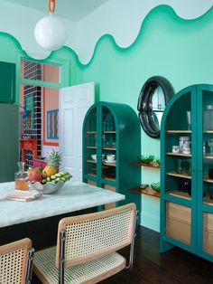 a kitchen with green walls and wooden chairs