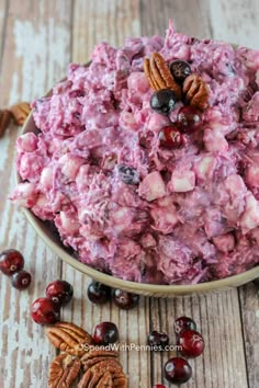 a bowl filled with fruit and nuts on top of a wooden table next to some pecans