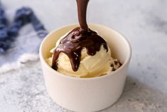 an ice cream sundae with chocolate drizzled on top, in a white bowl