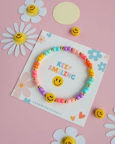 a bracelet that says keep smiling with smiley faces on it and some flowers around it