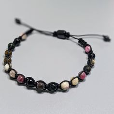 High Quality Pink & Black Agate Bracelet for men. Agate symbolizes strength, protection, and courage. Simple contemporary design Weight: 15 grams Bead size: Black braided cord Adjustable macrame knot One size fits all Adjustable Black Hand-strung Braided Bracelet, Black Braided Bracelets With Adjustable Cord And Round Beads, Black Braided Bracelet With Adjustable Cord And Round Beads, Black Braided Bracelet With Round Beads, Black Jewelry With Adjustable Cord For Healing, Adjustable Braided Bracelets With 8mm Beads For Healing, Adjustable Braided Bracelets With Natural Stones For Friendship, Black Macrame Jewelry For Friendship, Spiritual Braided Bracelets With Round Beads And Adjustable Cord