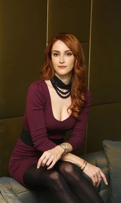 a woman sitting on top of a couch wearing black tights and a purple dress