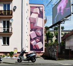 a scooter parked in front of a building with a large painting on it