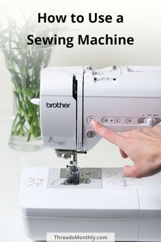 someone is using a sewing machine to sew something on the table with flowers in the background