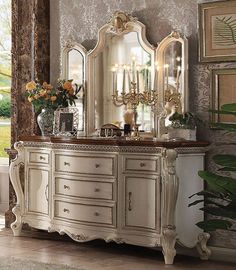 an ornate white dresser with mirrors and vases