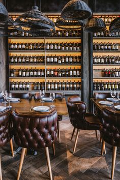 an empty restaurant with leather chairs and tables in front of shelves full of wine bottles